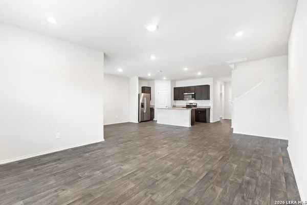 a view of kitchen with microwave oven stove refrigerator and white cabinets with wooden floor