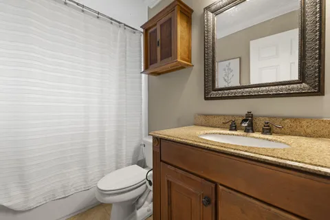 a bathroom with a granite countertop sink vanity mirror and toilet