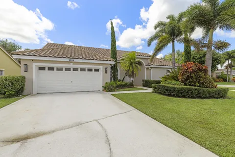 a view of a house with a yard and palm trees