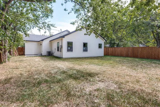 a view of a house with a yard and large tree