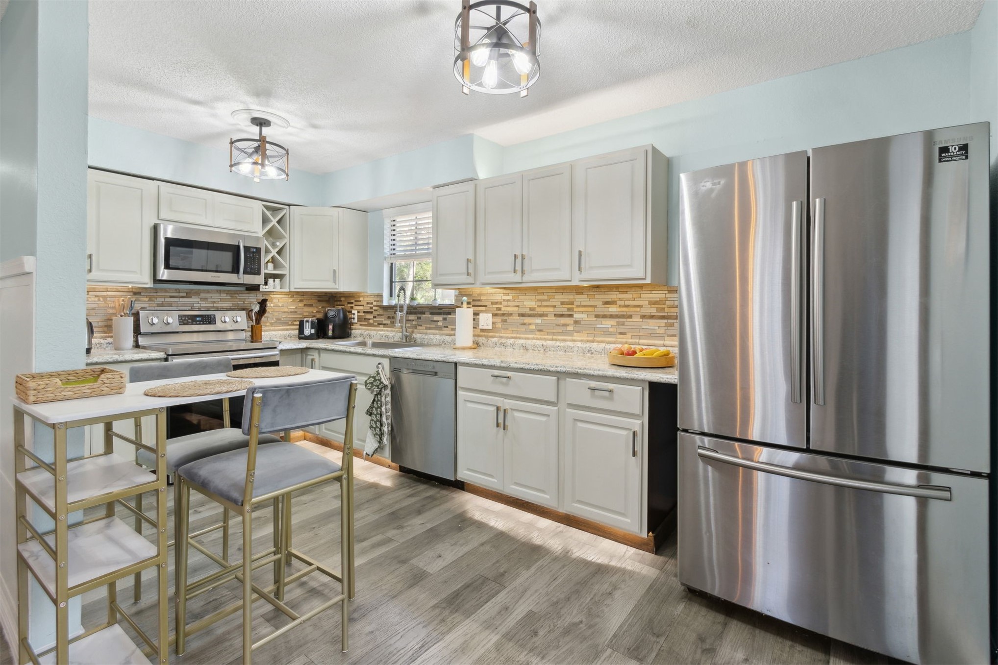 97471 Cutlass Way Yulee, FL 32097 - Photo 10 of 56 a kitchen with kitchen island granite countertop stainless steel appliances a sink a stove a refrigerator cabinets and dining table