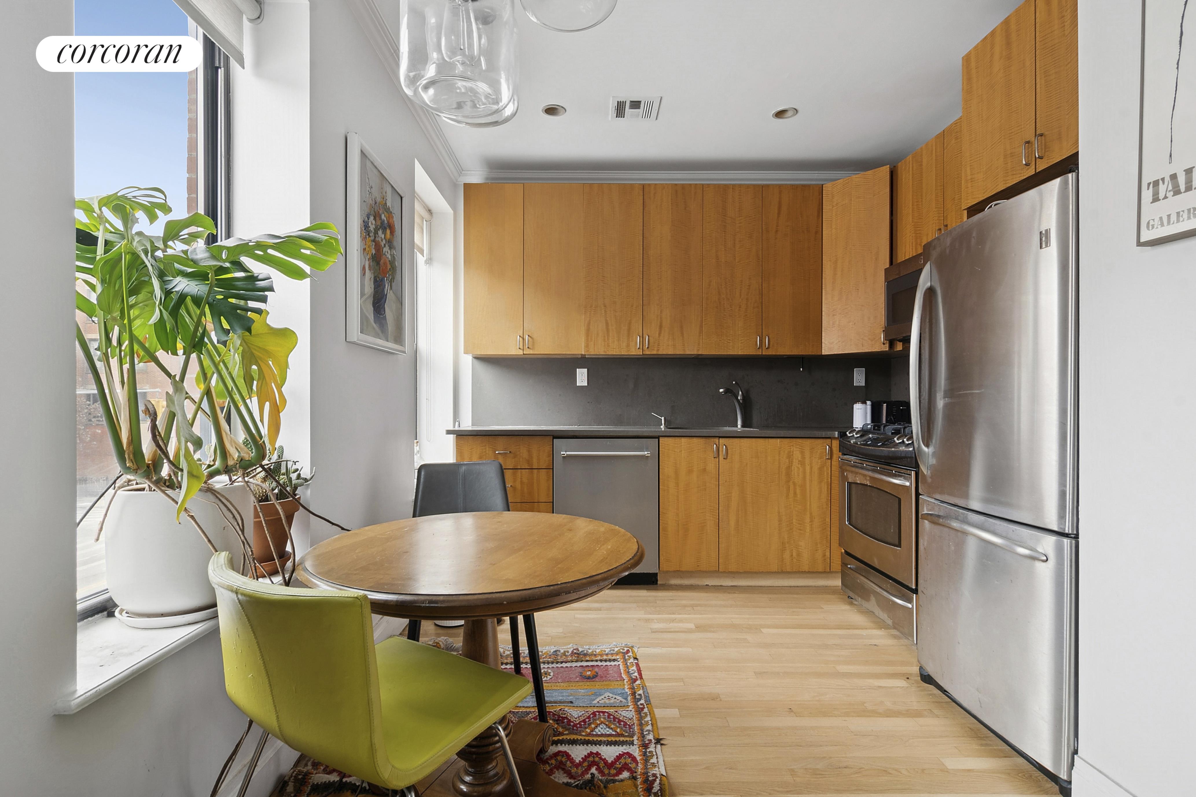 445 3rd Avenue, Unit 202 Brooklyn, NY 11215 - Photo 2 of 6 a kitchen with stainless steel appliances granite countertop a refrigerator a stove a sink a dining table and chairs with wooden floor