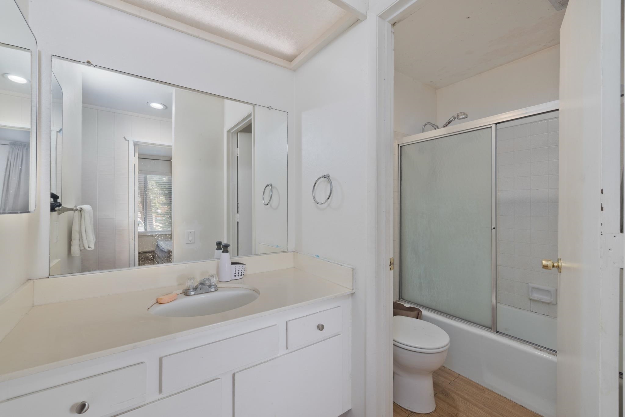 25 Lee Road, Unit 103 Mammoth Lakes, CA 93546 - Photo 19 of 29 Bathroom featuring a white vanity with integrated sink, a large wall-mounted mirror, white cabinetry, and a shower-over-tub with sliding glass doors