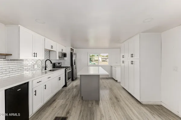 a large kitchen with a lot of counter space and wooden floor