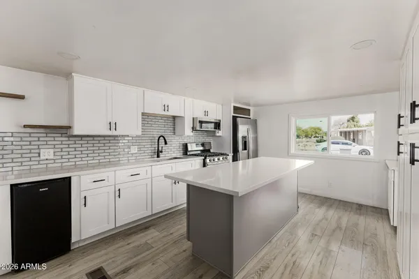 a large white kitchen with cabinets a sink and appliances