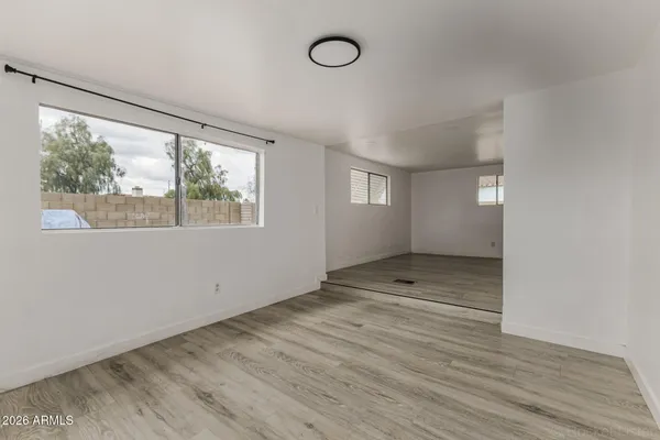 a view of empty room with wooden floor and fan