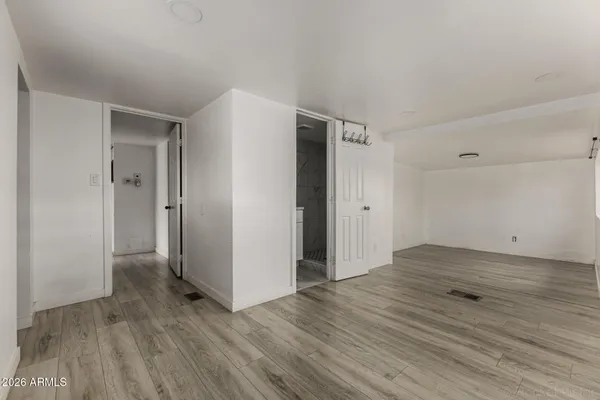 a view of an empty room with wooden floor and a window