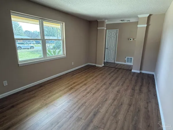 a view of wooden floor in an empty room with a window