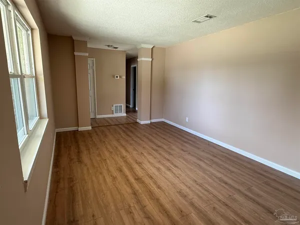 a view of an empty room with wooden floor and a window