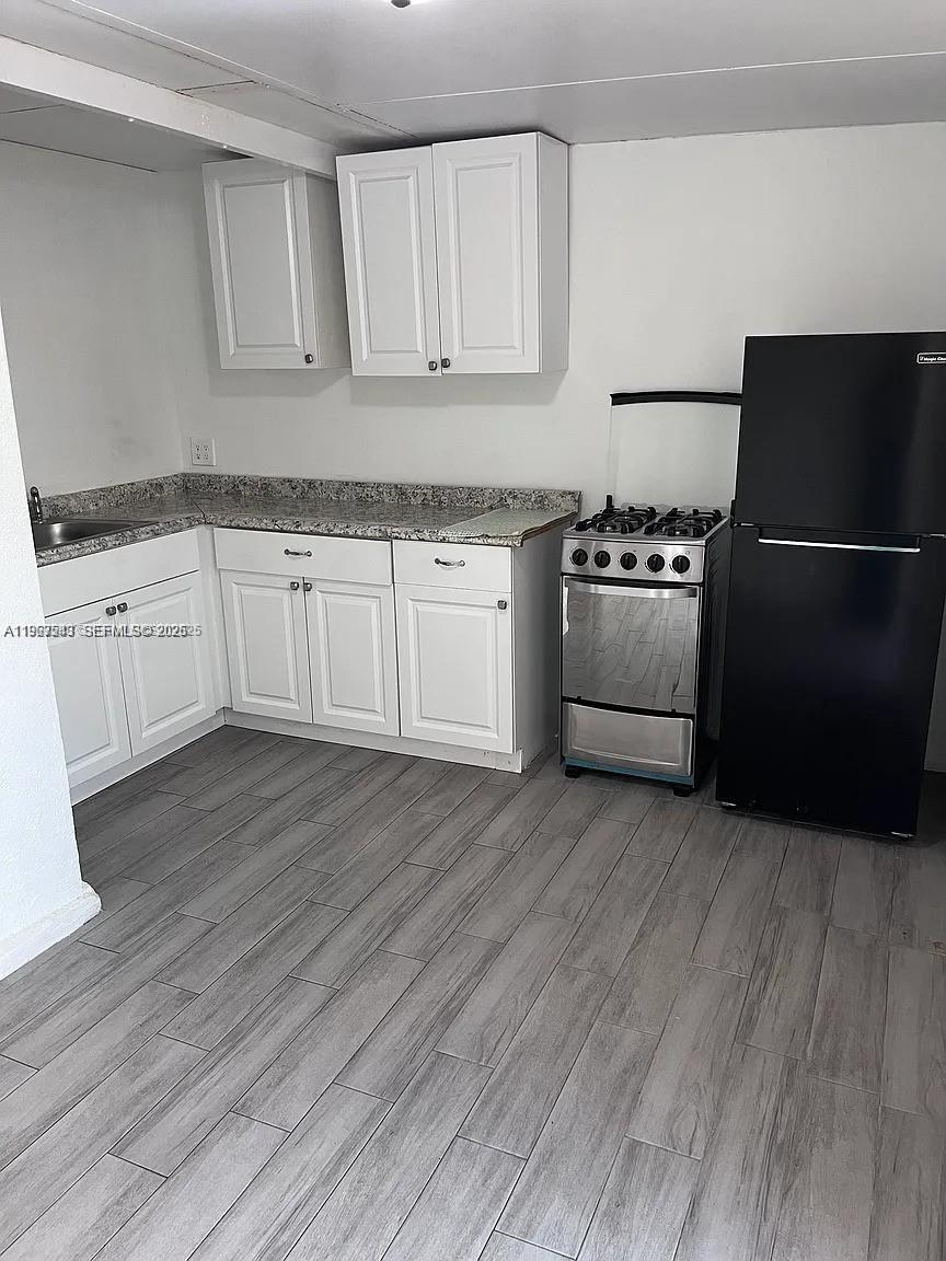 27 Southwest 55th Avenue Road Miami, FL 33134 - Photo 4 of 17 a kitchen with granite countertop white cabinets and stainless steel appliances