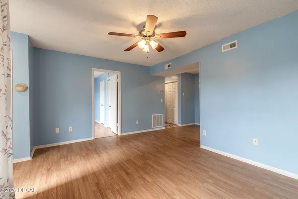 a view of an empty room with chandelier fan and a window