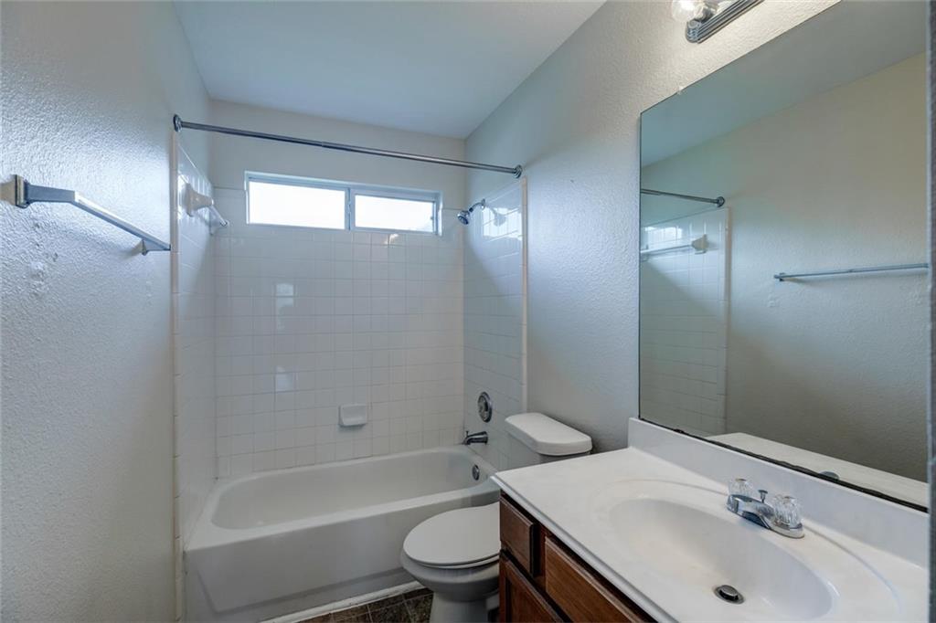 16712 Hamilton Point Circle Manor, TX 78653 - Photo 18 of 38 Tiled shower surround and integrated vanity sink highlight this classic bathroom design.
