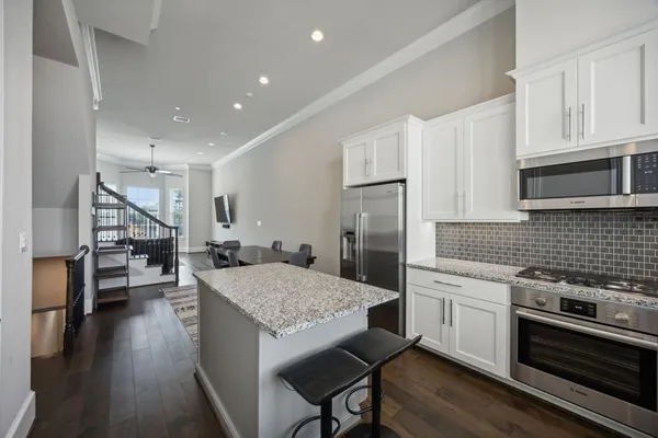 a kitchen with stainless steel appliances granite countertop a kitchen island hardwood floor sink and stove