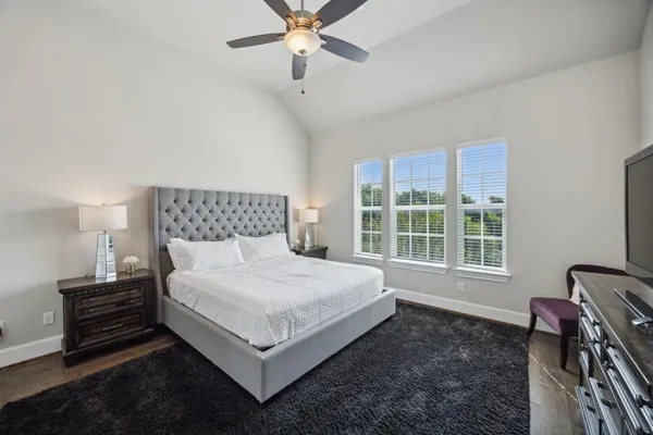 a bedroom with a bed table and two window