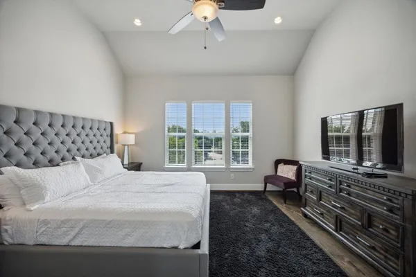 a bedroom with a large bed and a flat tv screen on dresser