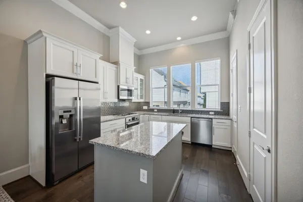 a kitchen with stainless steel appliances granite countertop a refrigerator a sink dishwasher a stove and white countertops with wooden floor