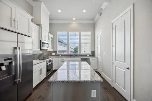 a large kitchen with stainless steel appliances granite countertop a refrigerator and a sink