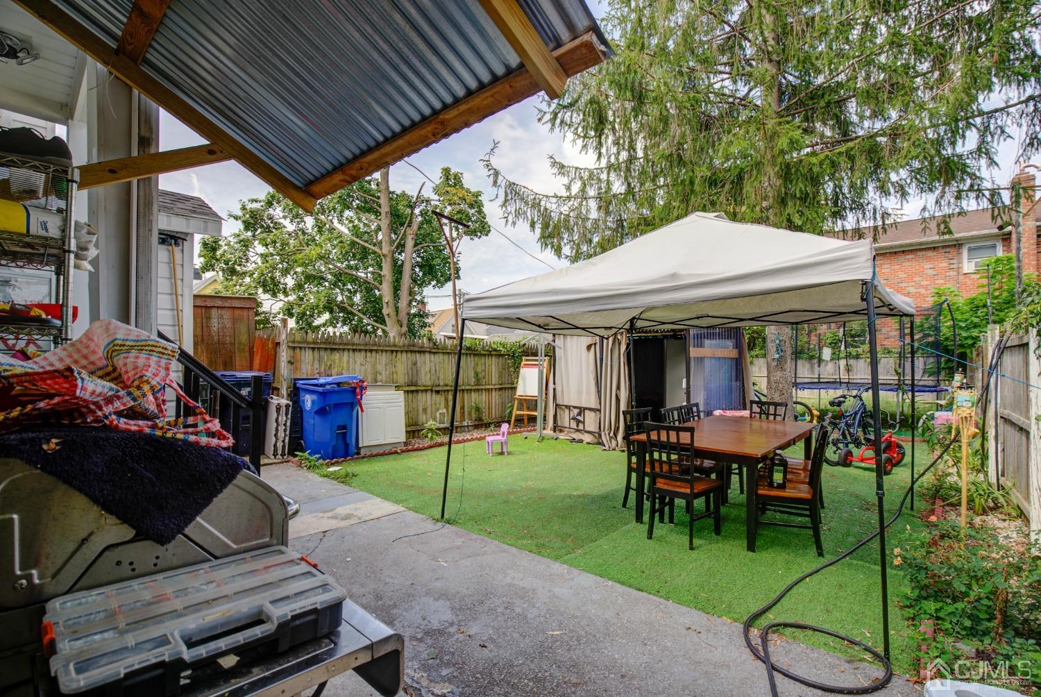 431 Baker Place Perth Amboy, NJ 08861 - Photo 4 of 16 a view of a patio with table and chairs under an umbrella with a small yard