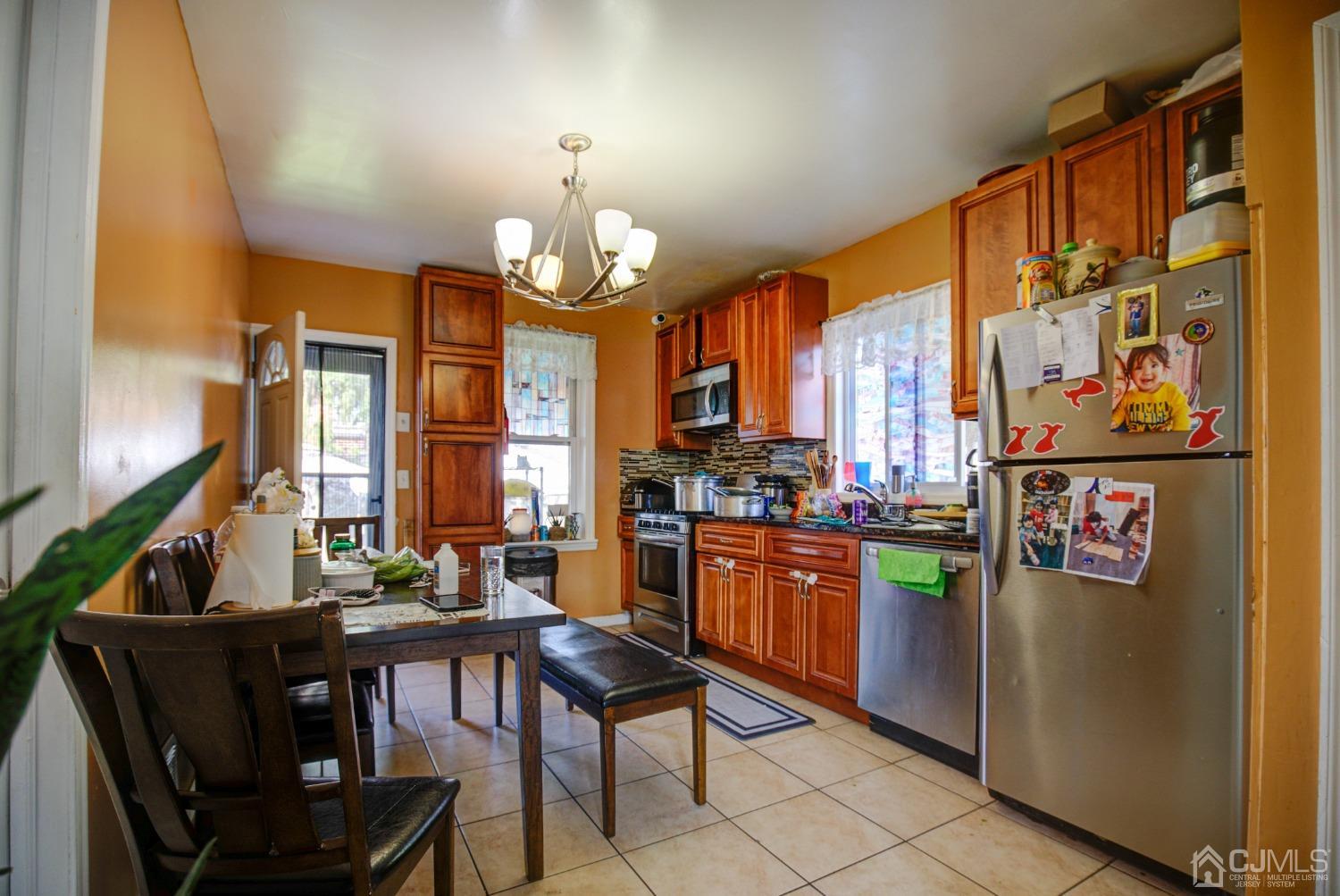 431 Baker Place Perth Amboy, NJ 08861 - Photo 8 of 16 a view of a dining room with furniture a kitchen and chandelier