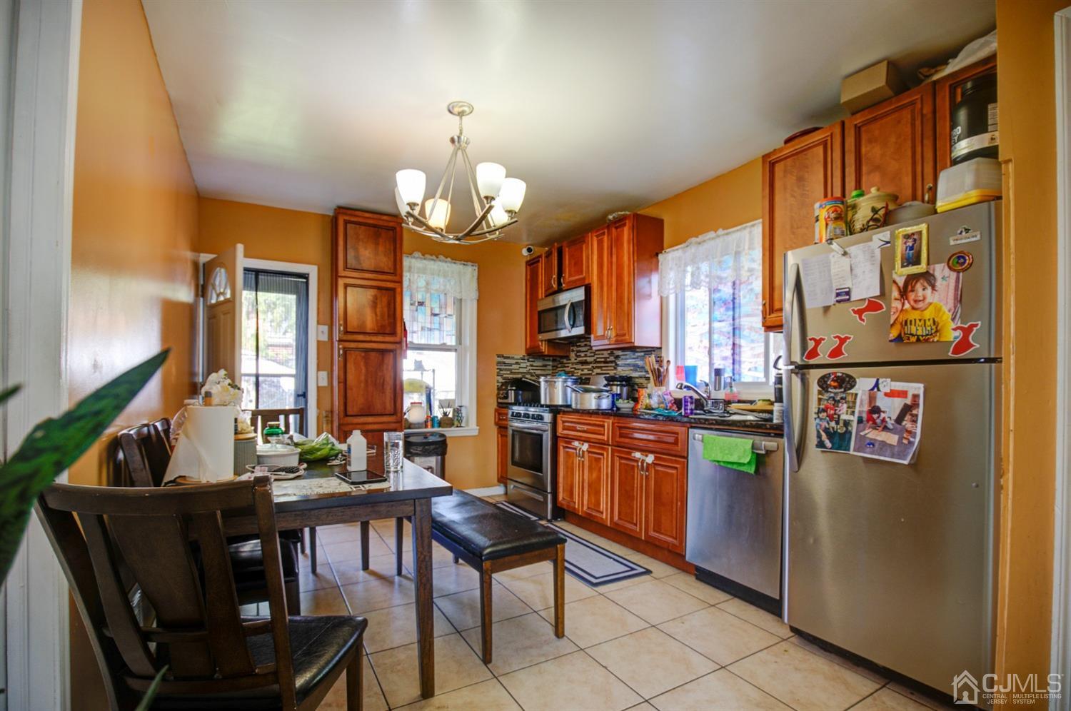 431 Baker Place Perth Amboy, NJ 08861 - Photo 10 of 16 a view of a dining room with furniture a kitchen and chandelier