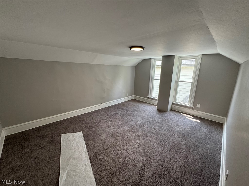 674-676 Carlysle Street Akron, OH 44310 - Photo 12 of 20 Carpeted bedroom 1 on second floor featuring two white-framed windows, sloped ceilings, and a flush-mount ceiling light fixture