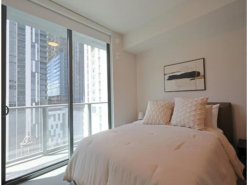 121 Northeast 5th Street Miami, FL 33132 - Photo 5 of 26 a bedroom with a large bed and a window