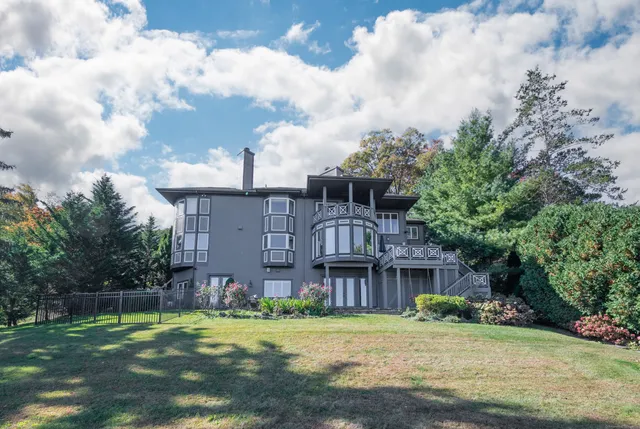 a view of a big house with a big yard and large trees
