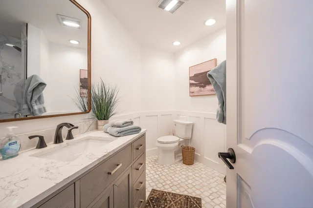 a bathroom with a granite countertop sink a toilet and a large mirror
