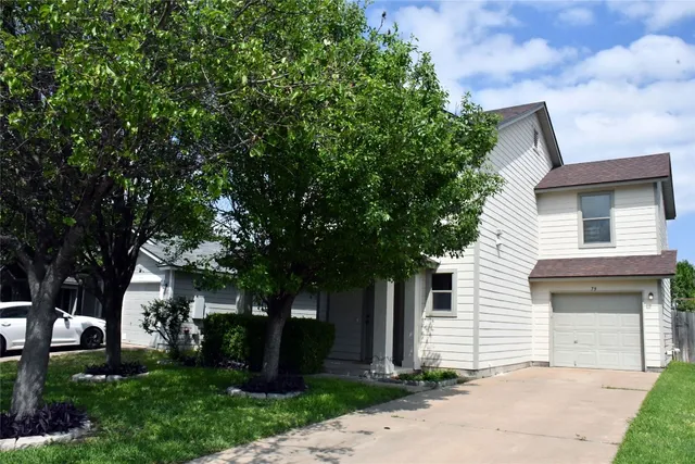 a front view of a house with a garden and tree