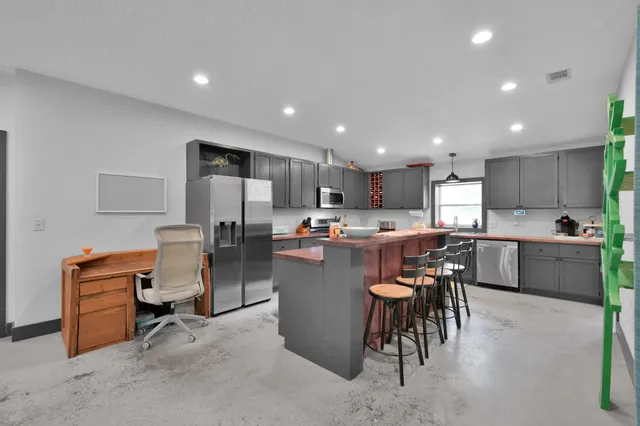 a view of kitchen with kitchen island stainless steel appliances refrigerator stove dining table and chairs