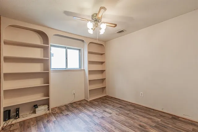 a view of an empty room with a window and wooden floor