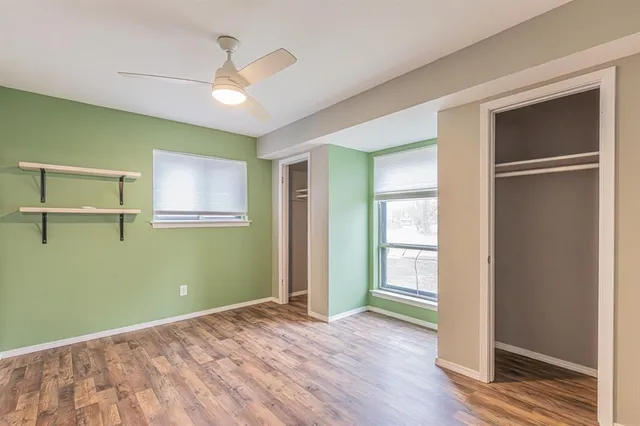 a view of empty room with wooden floor and fan