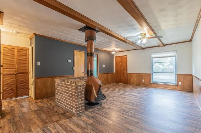 a view of an empty room with wooden floor and windows