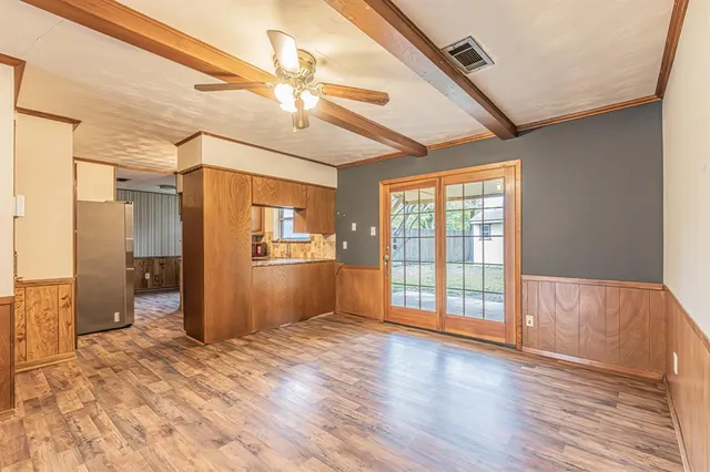 a view of an empty room with window and wooden floor