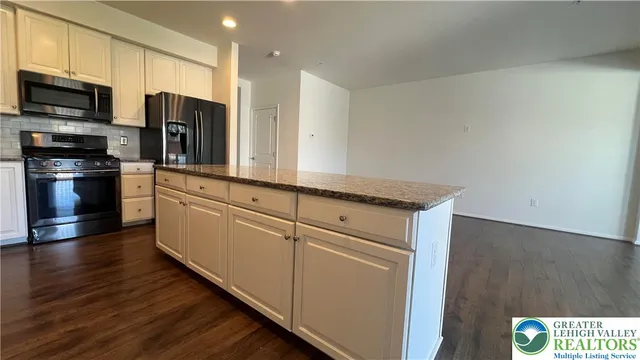 a kitchen with stainless steel appliances granite countertop a refrigerator a stove top oven a sink and dishwasher