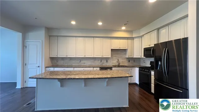 a kitchen with stainless steel appliances granite countertop a refrigerator a sink and a stove