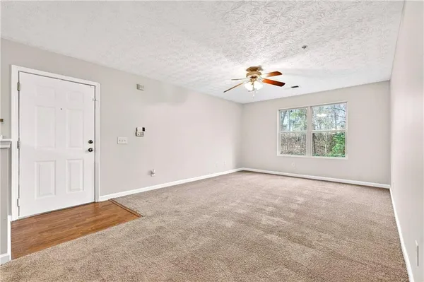 an empty room with windows chandelier fan and windows