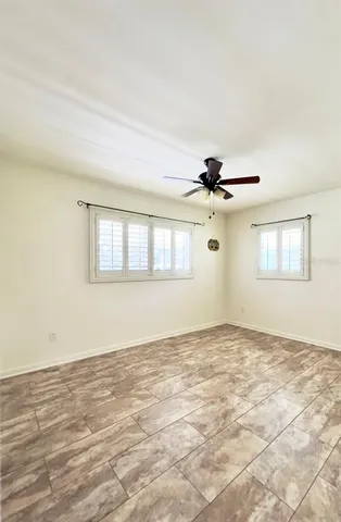 an empty room with windows and ceiling fan