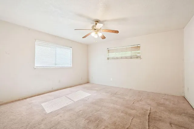 an empty room with windows and fan