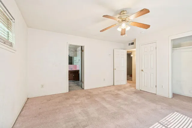 an empty room with closet and ceiling fan