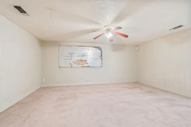 an empty room with windows and fan