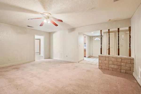 an empty room with chandelier fan and windows