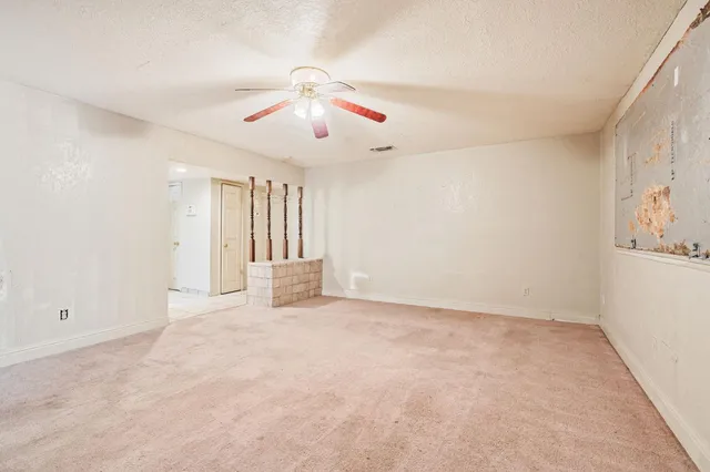 an empty room with chandelier fan and windows