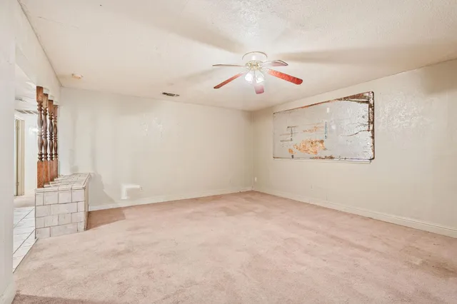 an empty room with windows and chandelier fan