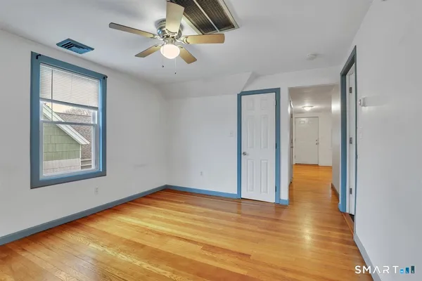 a view of empty room with wooden floor and fan