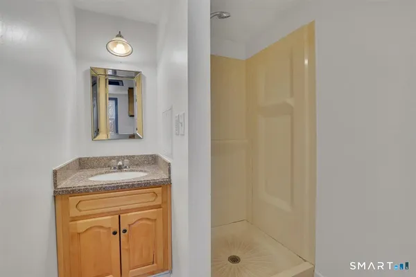 a bathroom with a granite countertop sink a mirror and shower
