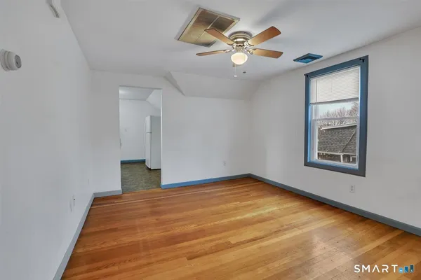 a view of a big room with wooden floor and chandelier fan