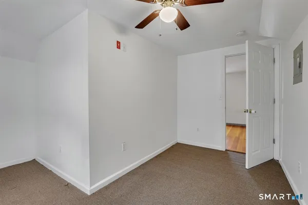 an empty room with a ceiling fan and carpet