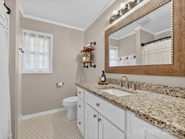 a bathroom with a granite countertop sink a toilet and a mirror