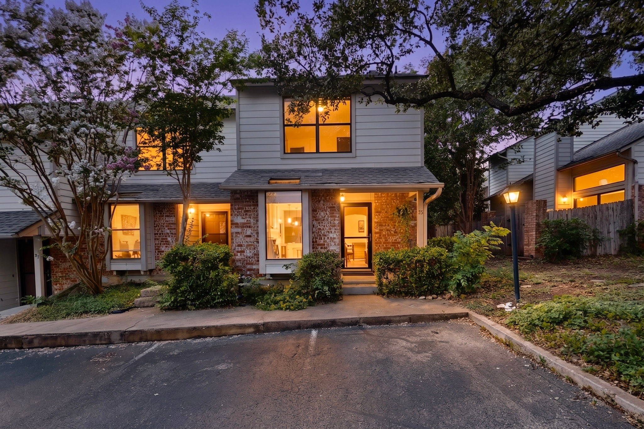 A welcoming front entrance features brick accents and well-maintained shrubbery under the soft glow of evening.